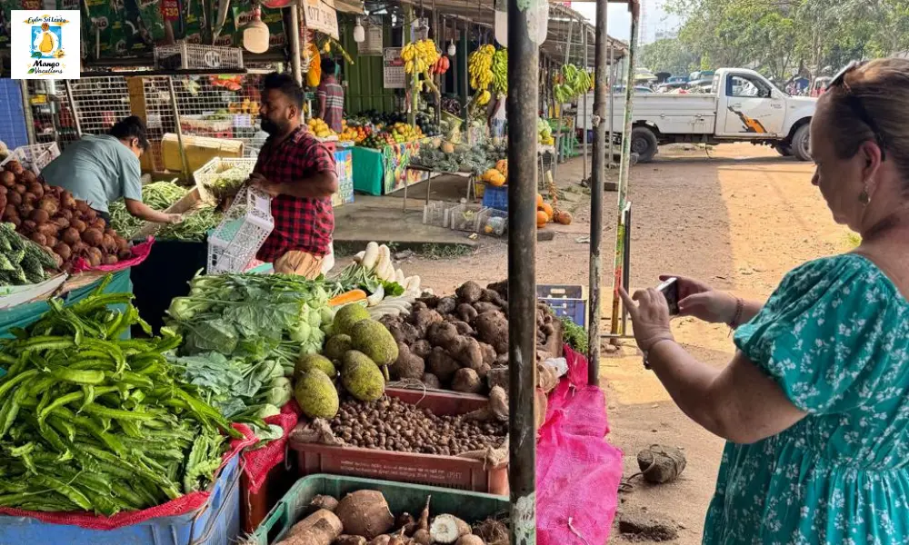 A traveler explores a vibrant local market in Colombo, Sri Lanka, photographing colorful displays of fresh tropical fruits, vegetables, and local produce while vendors serve customers.